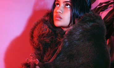 Junge Frau mit langen dunklen Haaren und Haarreif vor pinker Wand