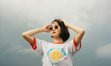 Junge Frau im T-Shirt vor grauem Himmel