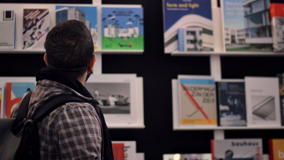 Man looking at a German Stories bookshelf