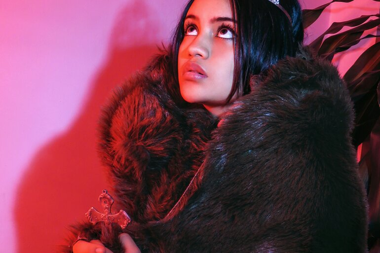 Junge Frau mit langen dunklen Haaren und Haarreif vor pinker Wand